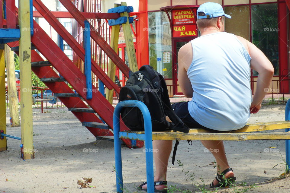 a man is sitting on a bench near a playground