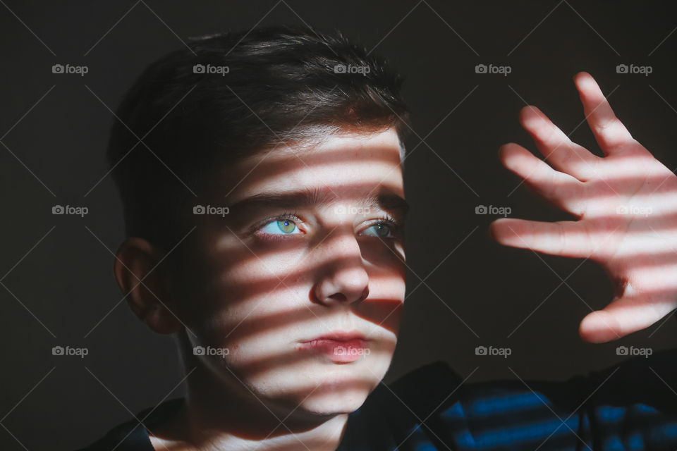 Portrait of boy against wall with sunlight falling on his face.