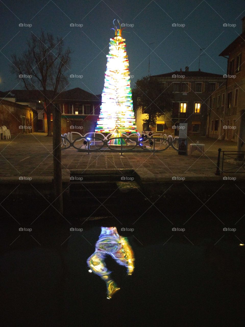 Glass Christmas tree on the island of Murano and its reflection in the canal