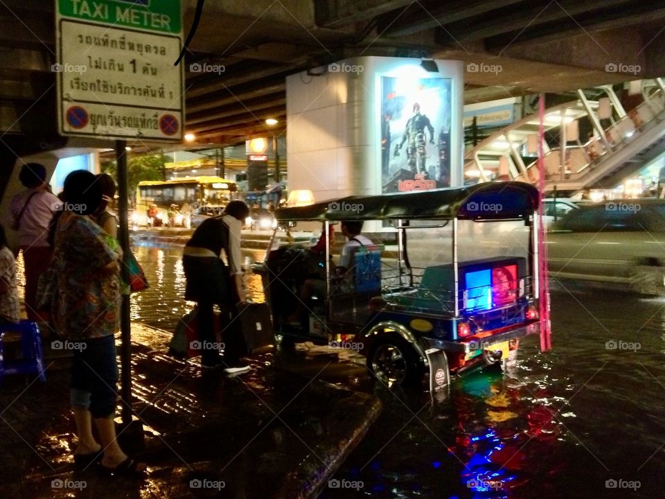 A tuk-tuk drives on while the streets flood in Bangkok, Thailand.