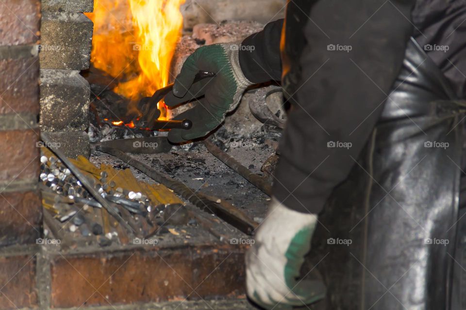 A blacksmith melts metal in a hot furnace.  Blacksmith workshop