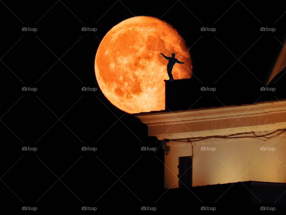 Silhouette of a man on the roof against the background of the moon