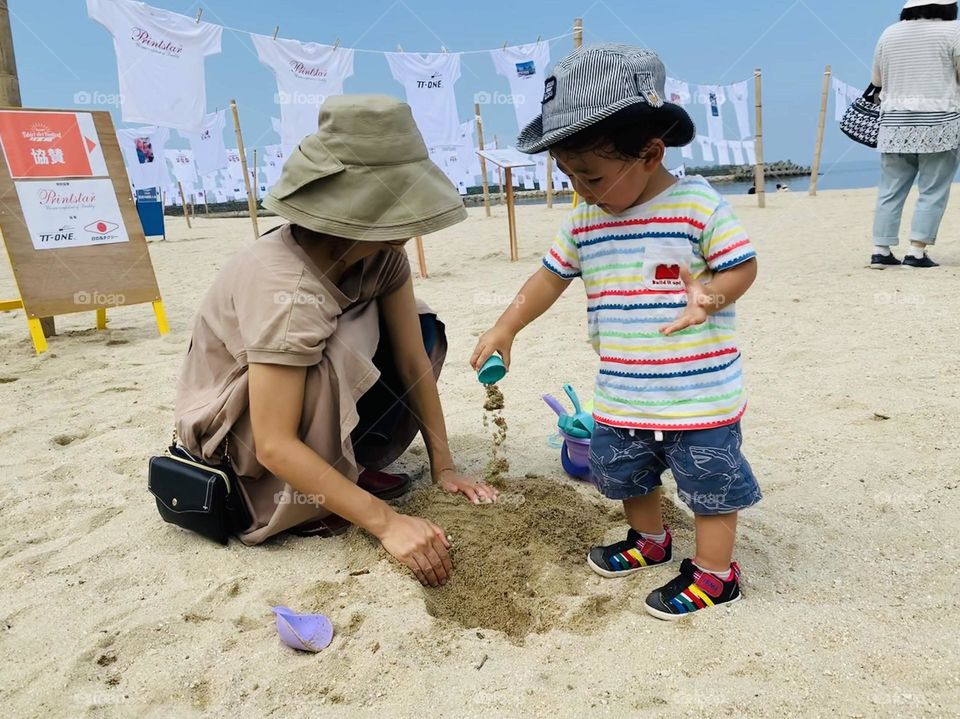 A mother is playing with a son on the beach
