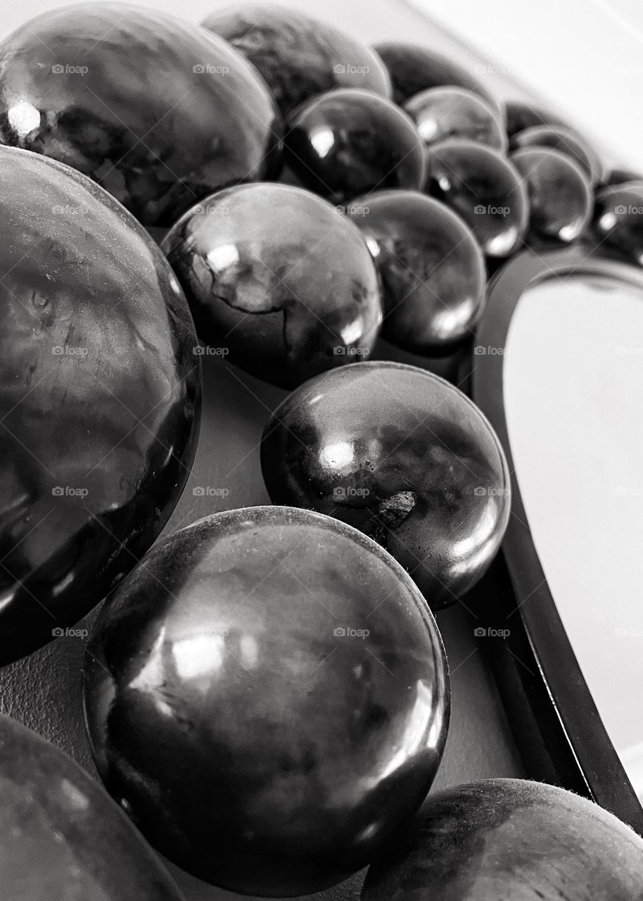 Close up of round metal pebbles surrounding a mirror creating a textured image in black and white