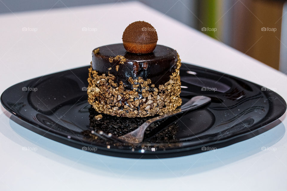 chocolate cake with walnuts on a black plate