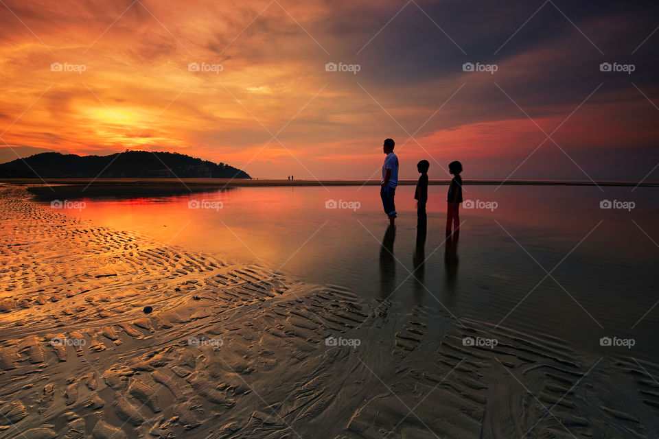Follow The Leader. A man with his two daughter stand still watching sunrise at Cherating Beach Pahang.