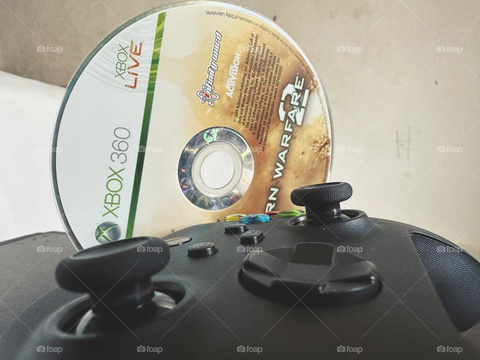 Video game disc modern warfare side by side with Xbox controller closed up.