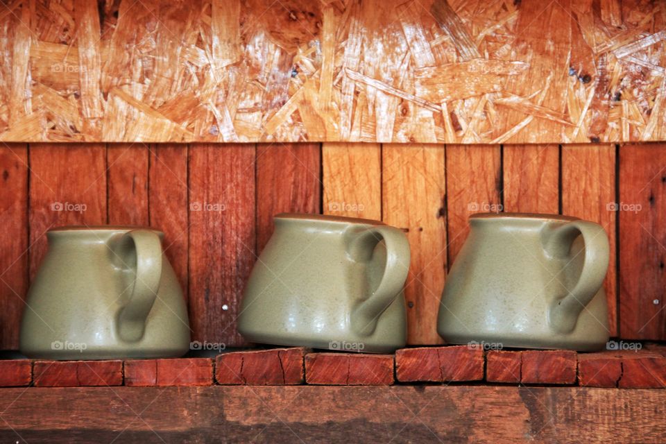 3 glasses of water made from pottery  Were arranged on a beautiful wooden shelf.