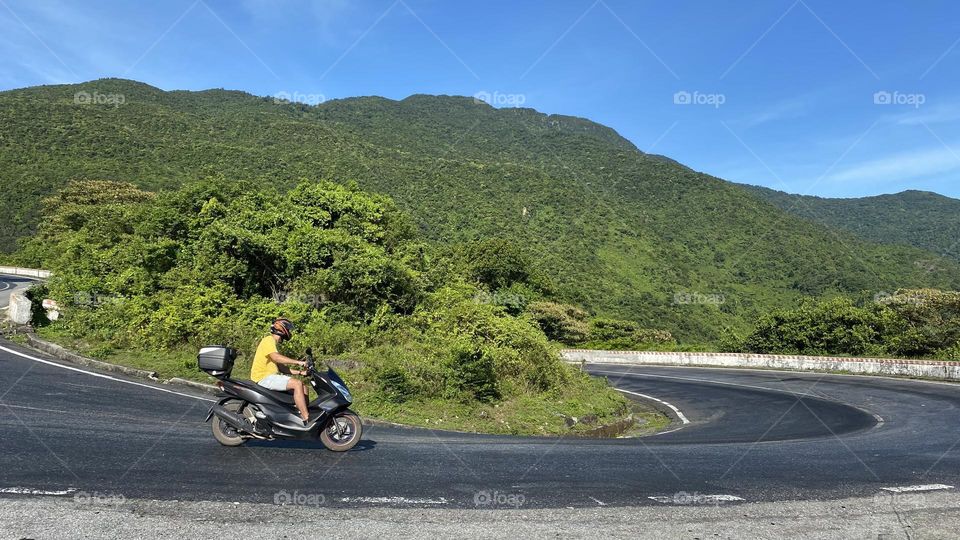 Young man driving the scooter on the windy road 