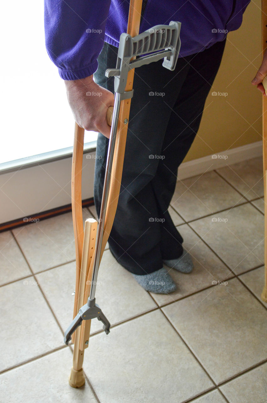 Woman using crutches with a reacher tool clipped on to them