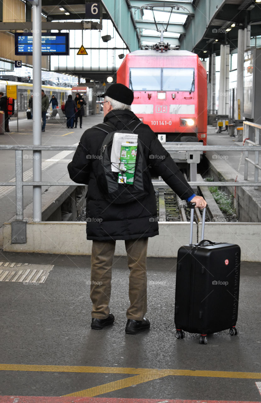 old man with suitcase and newspaper at the station