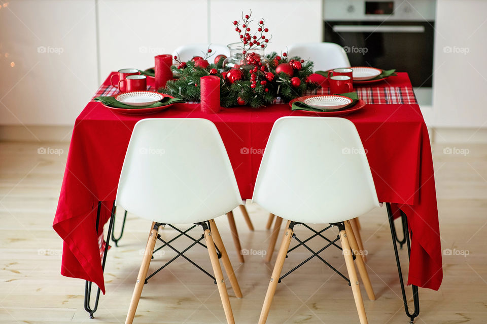 Festive winter cozy kitchen interior with garlands, decorations and gifts.  Christmas dinner at the decorated table.