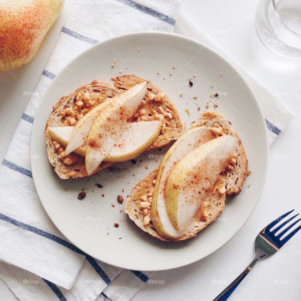 Healthy breakfast . Breakfast with sliced pear and peanut butter sprinkle with cinnamon on seven grains au levain toasts and coffee.