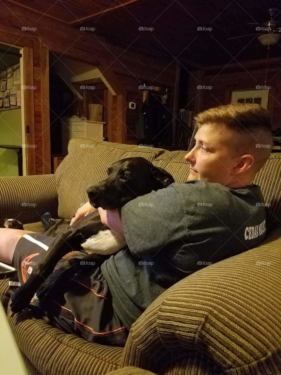 person and black dog cuddling on the couch