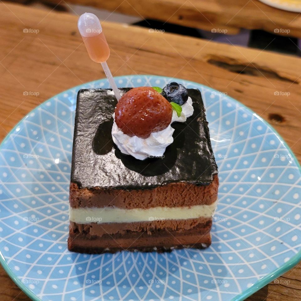 Chocolate cake with whipped cream, strawberries and blueberries paired with dropper wine