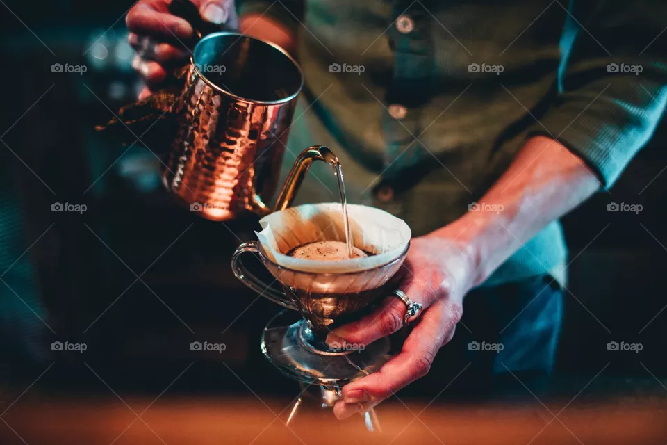 Barista vierte sobre el café de la tetera de cobre
