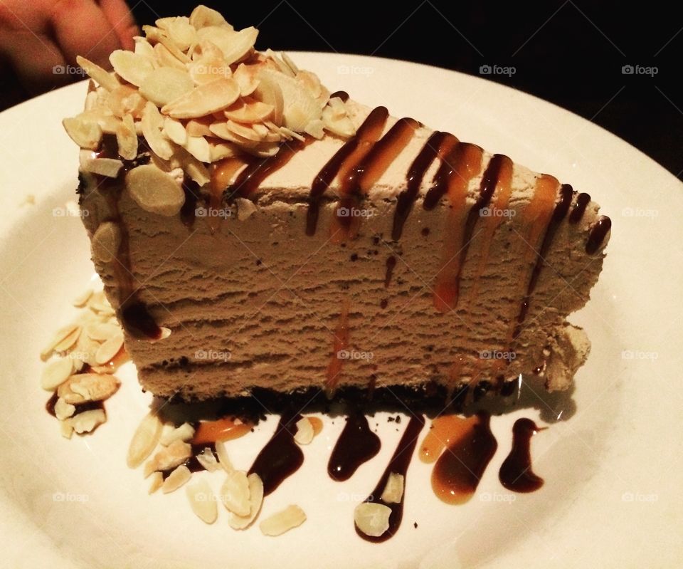 Chocolate ice cream cake with chocolate and caramel drizzle, almonds and whip cream. 