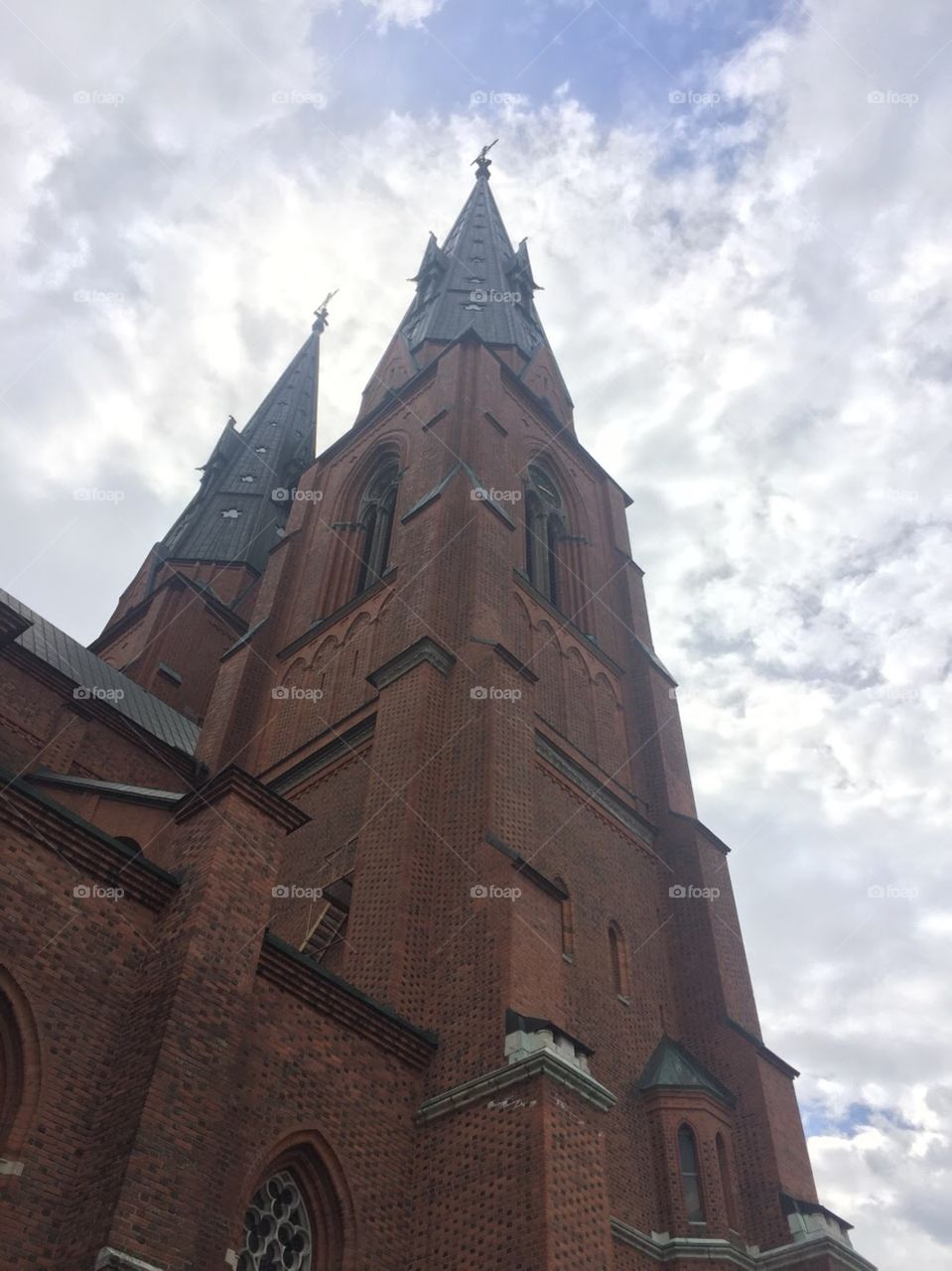 An old gothic church stands tall with beautiful architecture. Red brick is contrasted with the blue sky, pointy towers and large, ornate windows! 