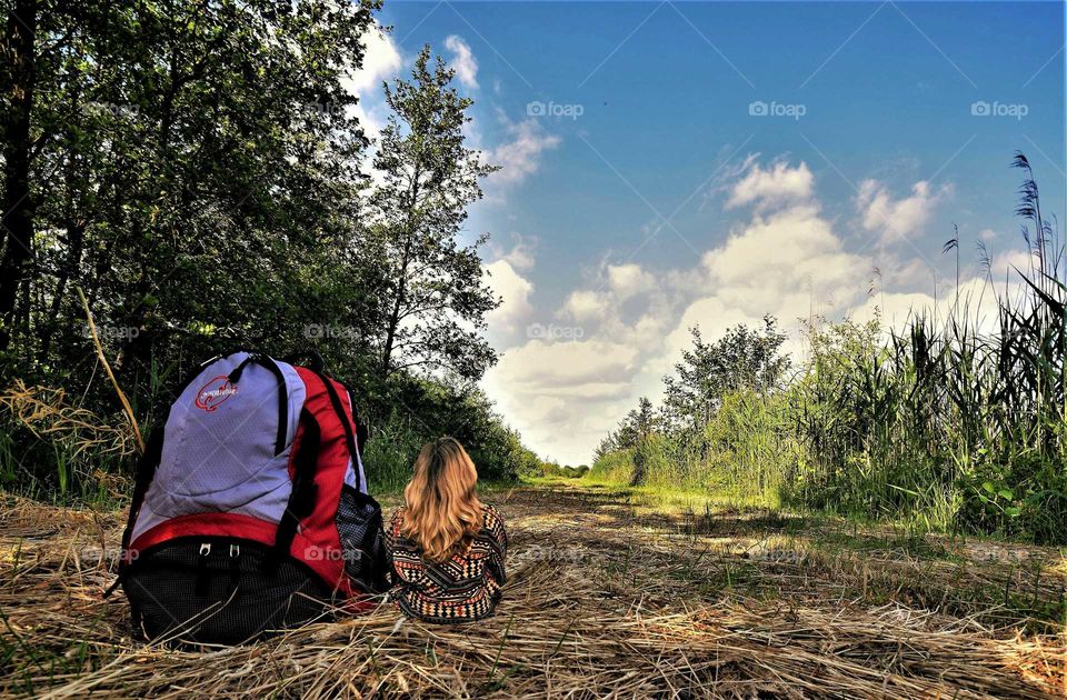 Funny forced perspective  picture woman with very large backpack in summer landscape