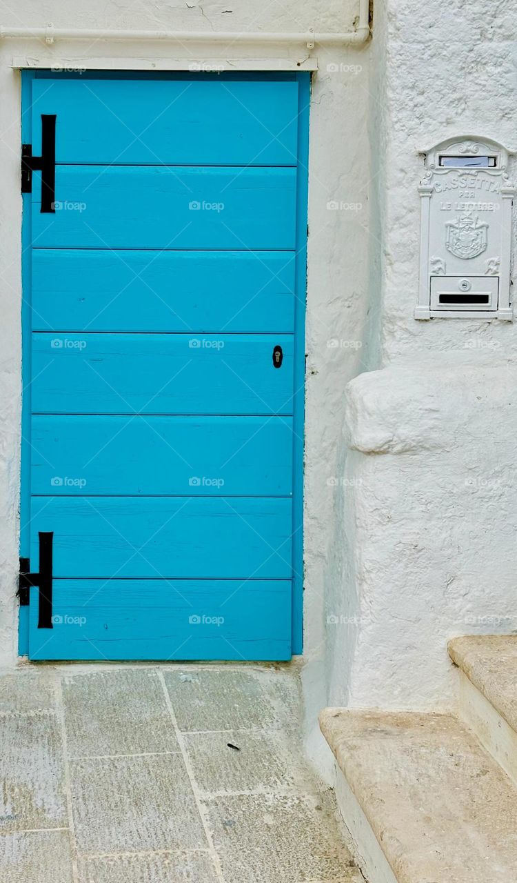 A sea blue door against a white washed building.