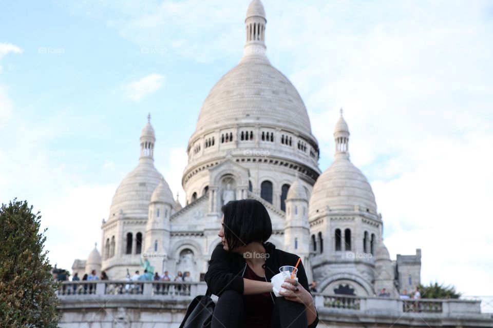 Girl sitting in front of the cathedral de Sacre Ceour in Paris, looking to her side.