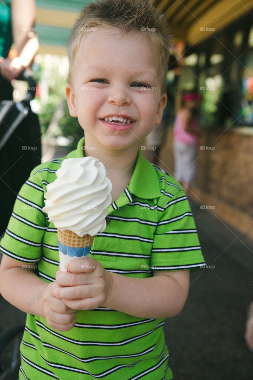 Young boy eating ice cream cone at the fair 