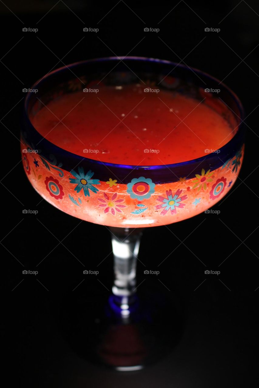 Yummy frozen strawberry margarita in festive margarita cup