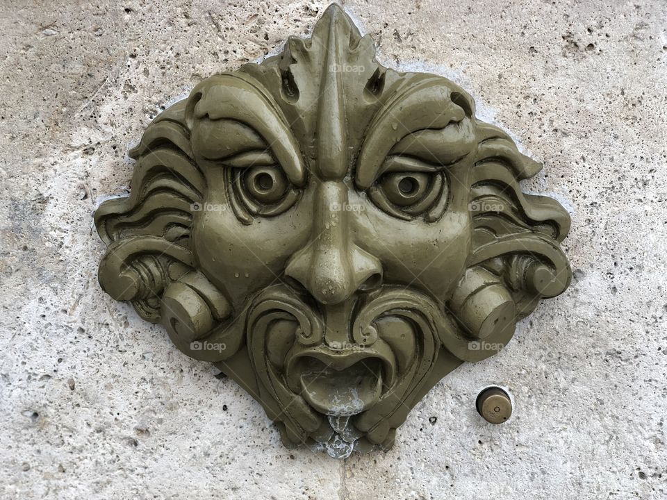 Detail view of the mask fountain, bronze mask, Fermo city, Marche region, Italy