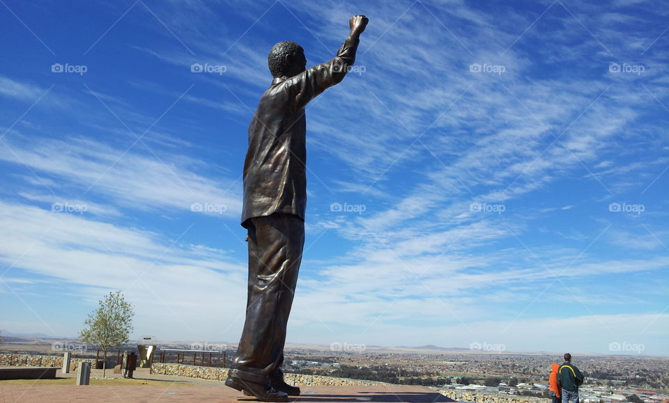 The statue of Nelson Mandela towers over the city of Bloemfontein in South Africa with high clouds in the sky