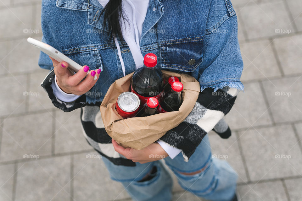 girl walks down the street and holds a package of Coca-Cola in her hands, spring, park