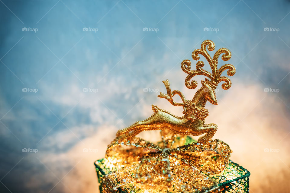 Christmas golden sparkling decoration deer on the gift box with lights on atmospheric sky background