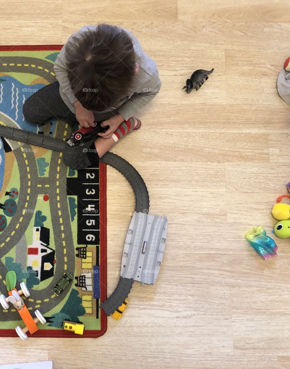 Child playing on floor with cars