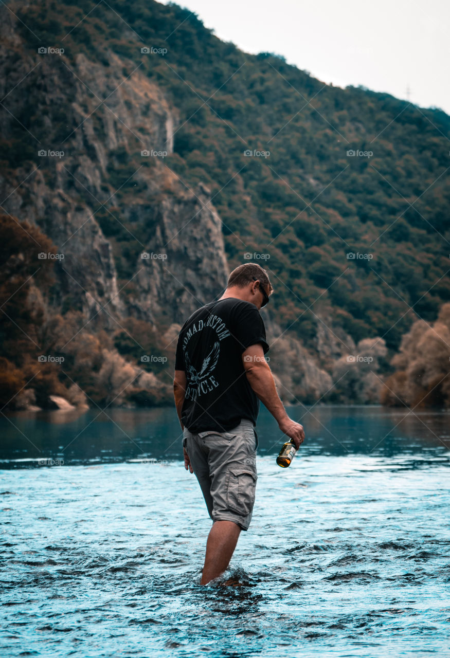 Man in a lake with a cold beer in the hand.