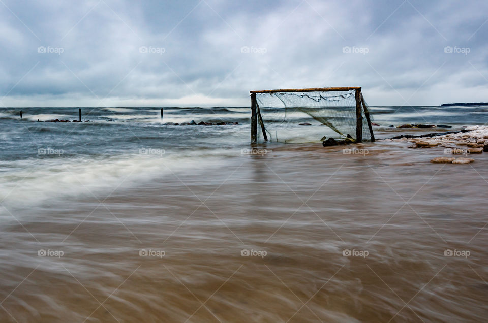 Storm in the Baltic sea beach. Water surounded by socer goal on the beach.