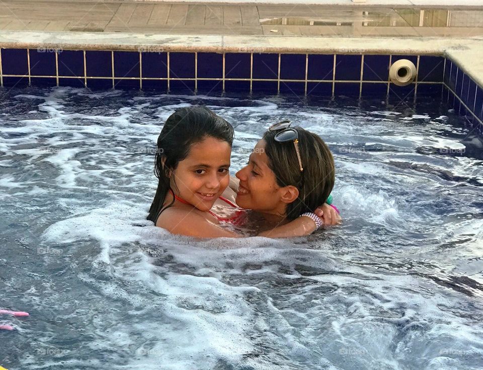 Mother and daughter hugging each other inside the pool.