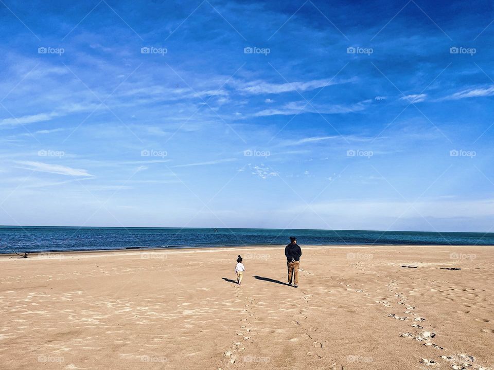 Mother and daughter walking on empty beach with their shadows, shadows on the beach, mother and daughter enjoying the beach, at the beach in the fall time, autumn beach visits, mother and daughter time together, family lifestyle 