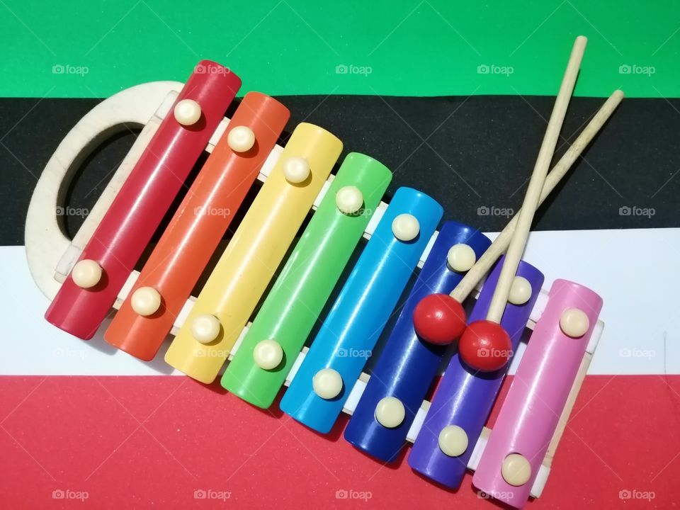 Rainbow colored wooden toy xylophone on colored background.