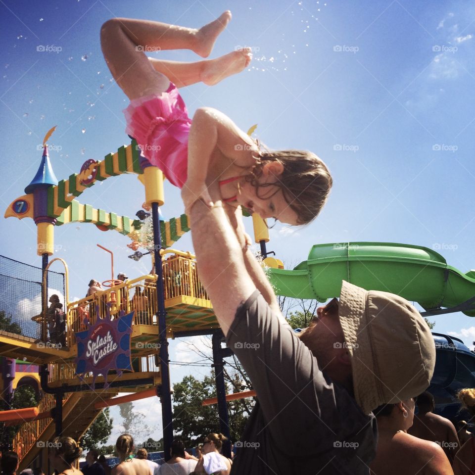 Child filled with joy at a water park with father. 