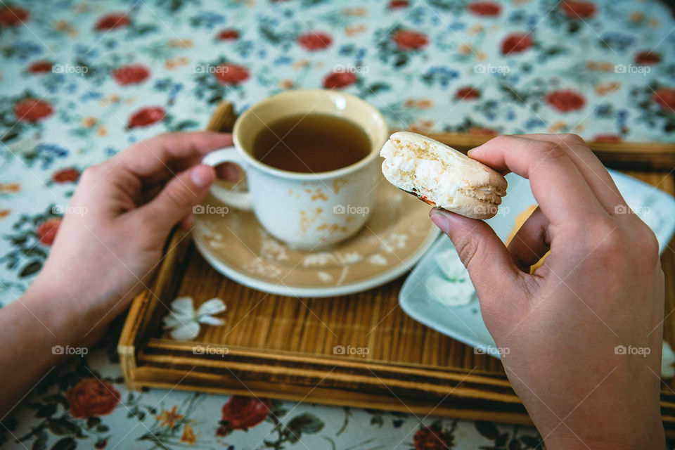 Human holding cookie with tea