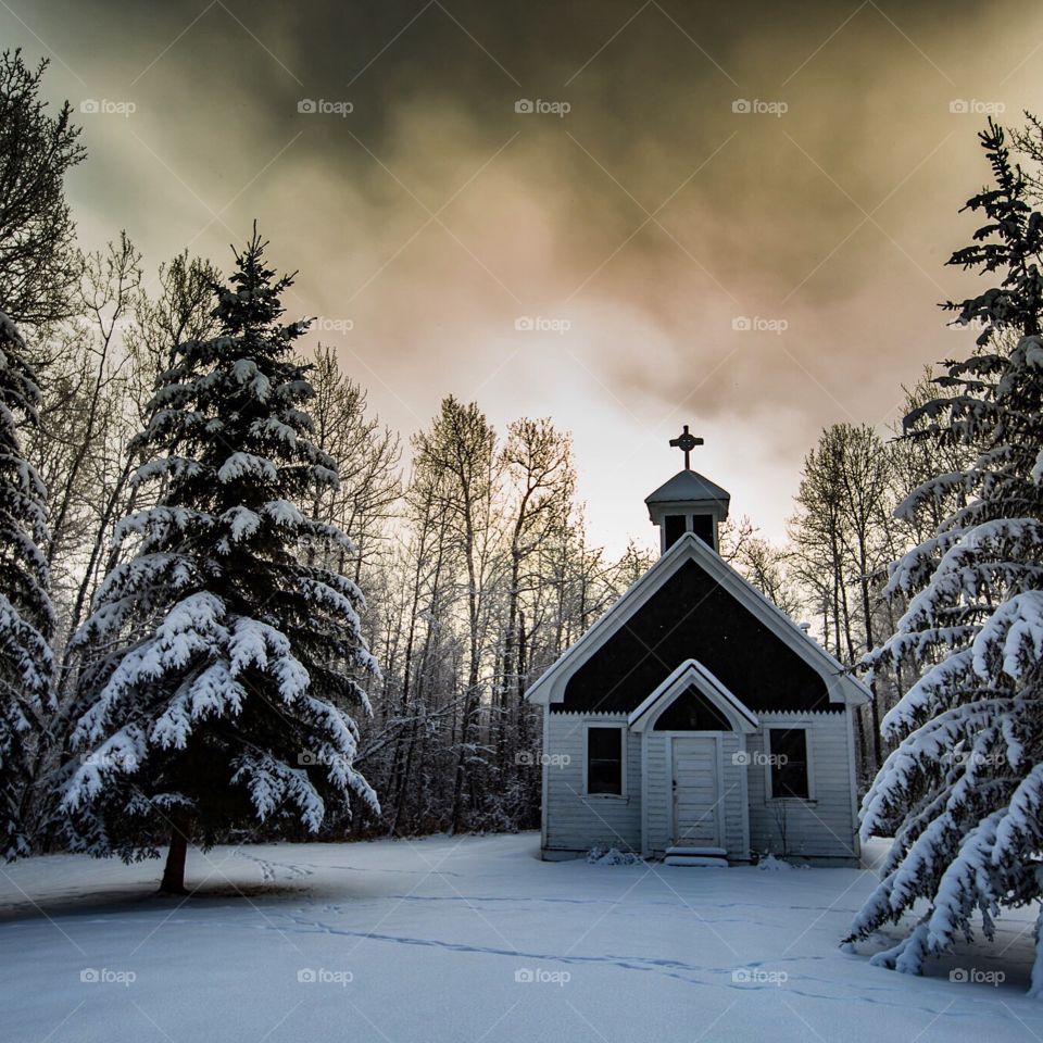 Winter scene of a historic church in a forest.