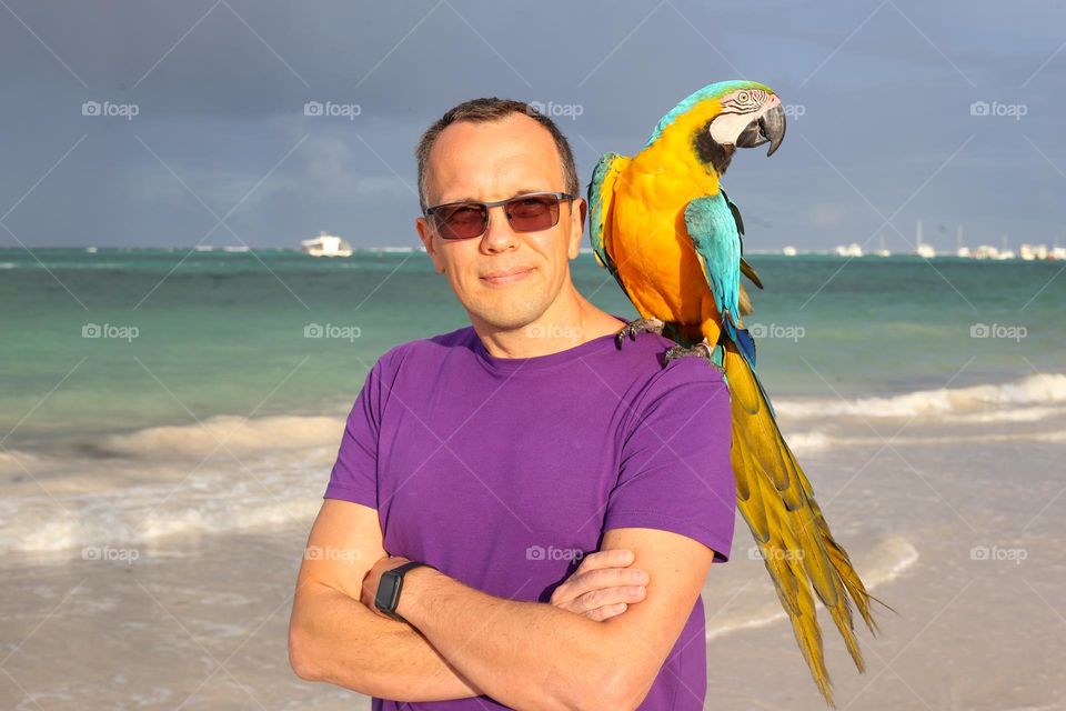 Nice man and colourful parrot. Holiday time. Beautiful Dominican Republic.