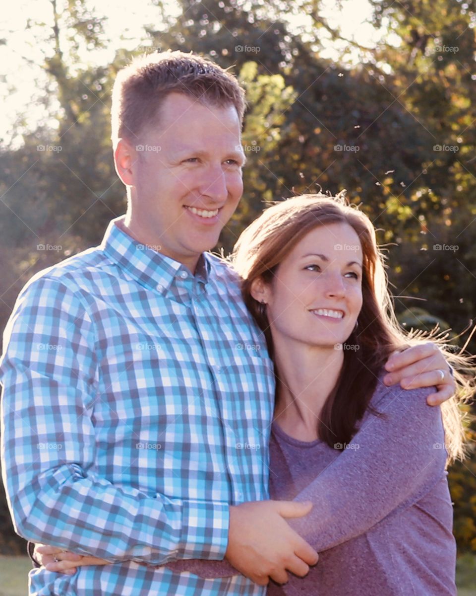 Backlight portrait of a husband and wife with arms around each other 