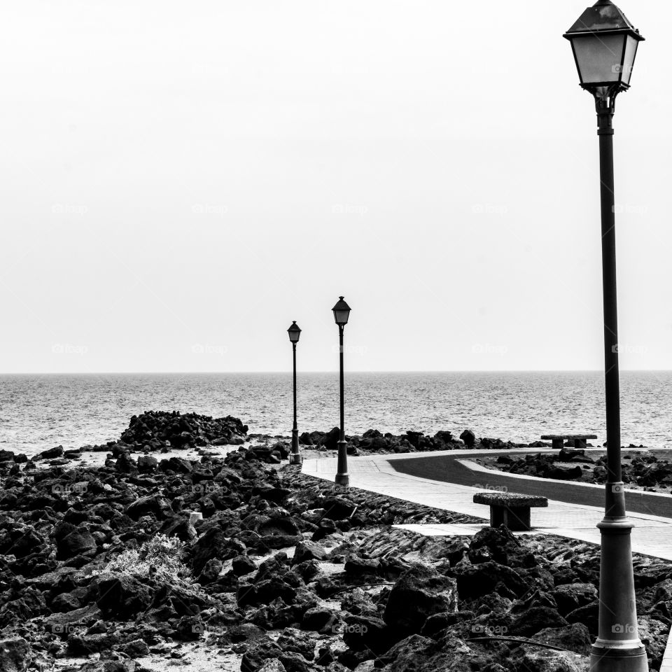 A black and white photograph of a beautiful promenade that runs all the way along the volcanic sea front in Caleta de fuste, on the island of Fuerteventura.