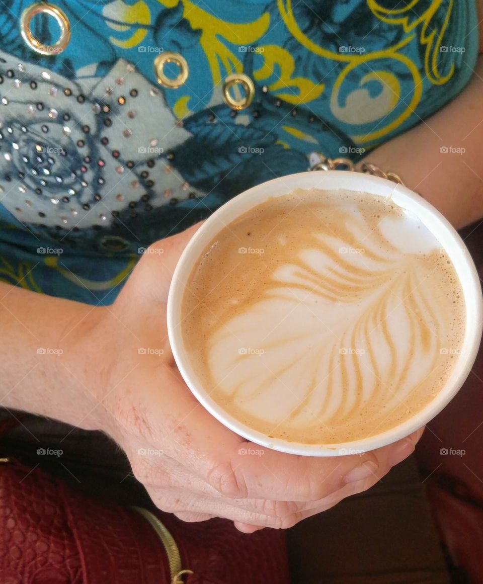 latte with leaf pattern in hands of woman