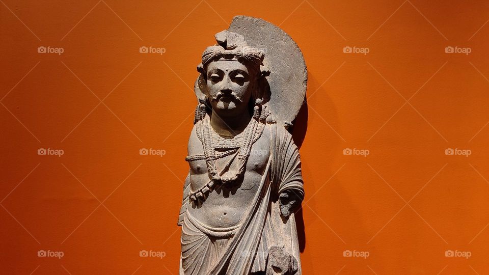 Decades Old king statue from India in clear orange background