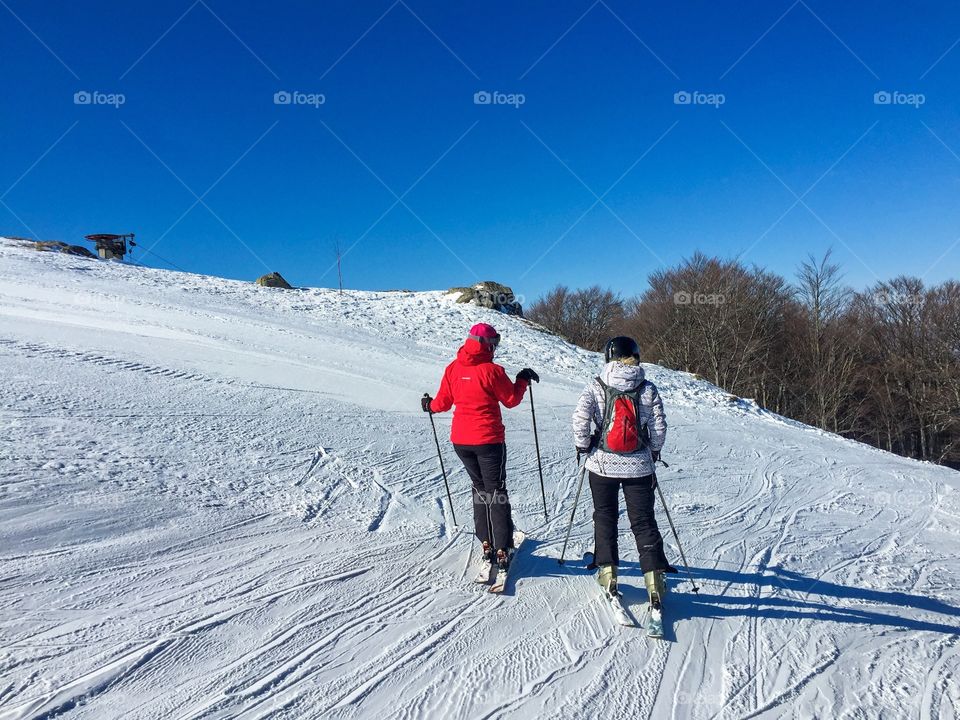 Two women skiers talking on the slope