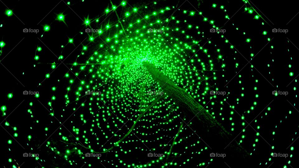 Under lighted green bulbs circling a pole.