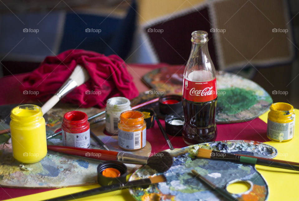 Coca-Cola bottles and colorful painting materials on the table