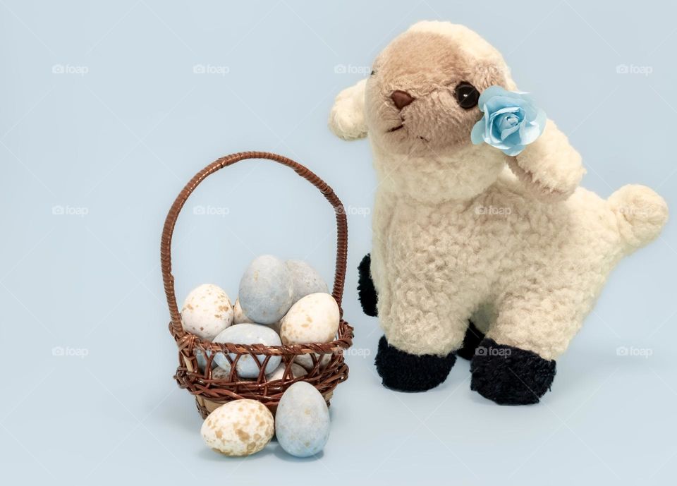 A plush toy of a spring lamb with a baskets of chocolate, speckled Easter Eggs