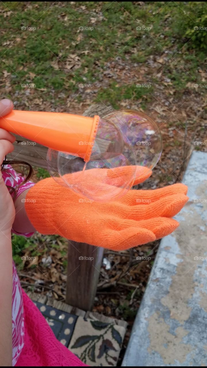 Close-up of girl's hand blowing bubble